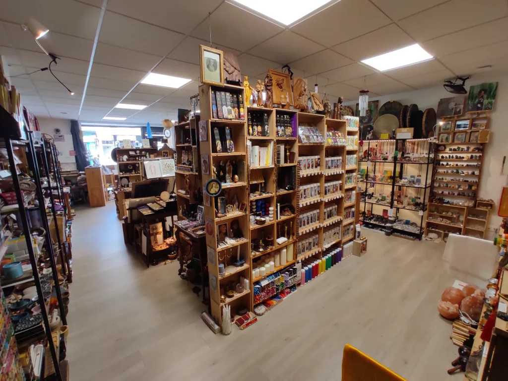 Intérieur d'une boutique d'articles ésotériques avec de nombreuses étagères chargées de produits, décorations et livres.