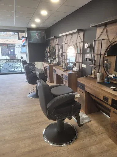 Intérieur d'un salon de coiffure moderne avec fauteuils en cuir noir, miroirs ronds et mobilier en bois style vintage.