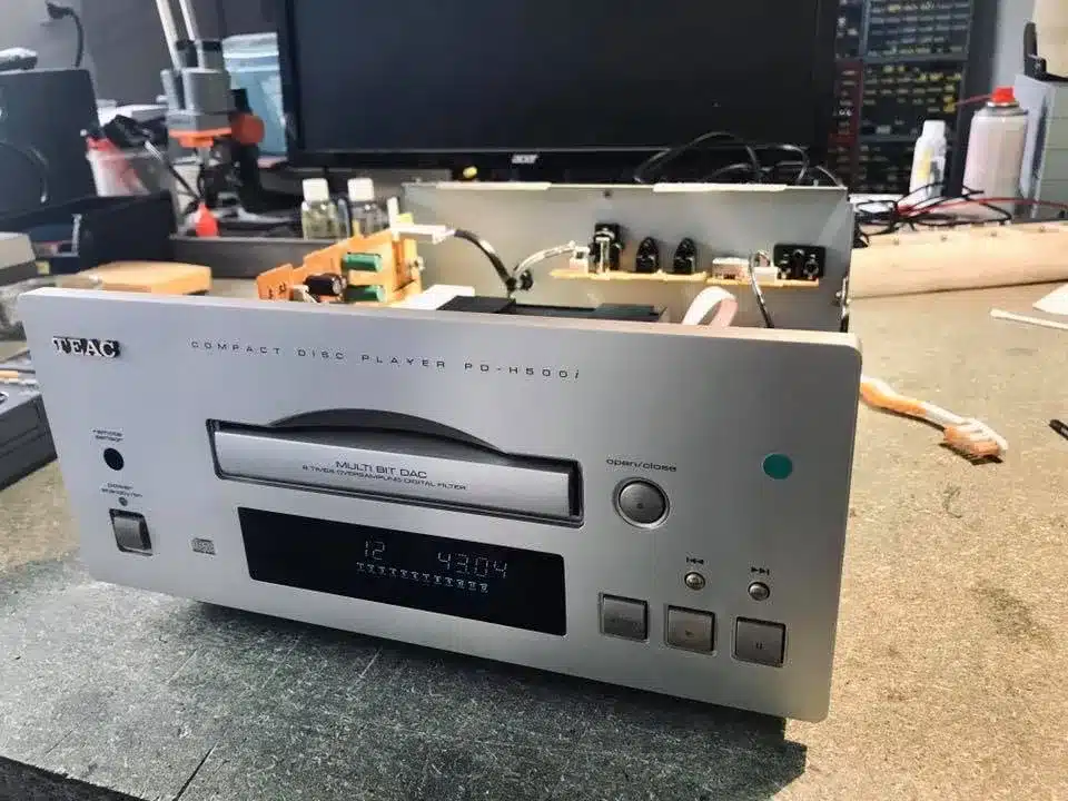 Lecteur CD TEAC PD-H800 argenté, de face, affichant l'heure et le chiffre 12, avec son tiroir CD partiellement ouvert et des composants internes visibles.