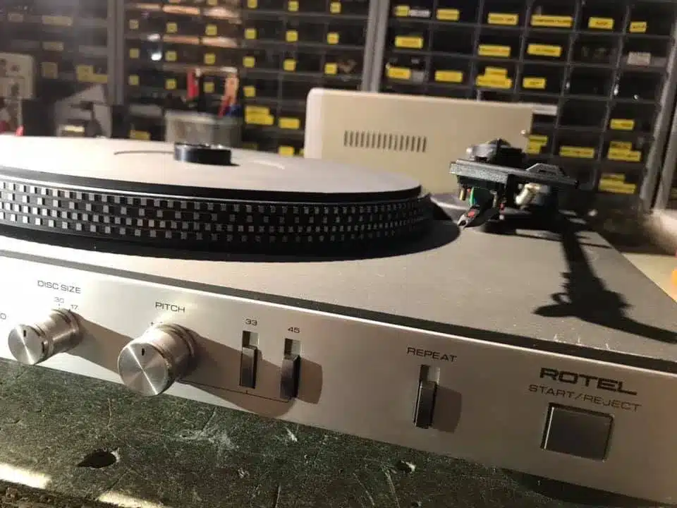 Platine vinyle Rotel avec ses commandes de volume, pitch, et sélection du disque. L'aiguille est visible.