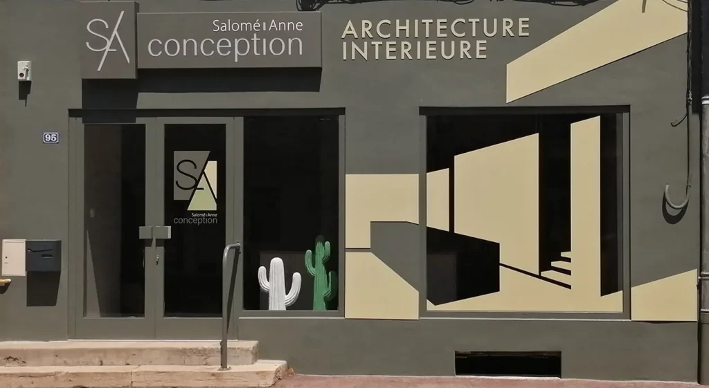 Façade d'un bureau d'architecture intérieure "Salomé Anne Conception" avec des cactus décoratifs dans la vitrine.